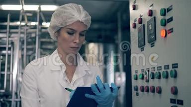 女工厂工人在一家<strong>乳品</strong>厂检查一台机器。